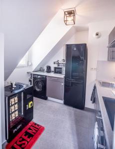 uma cozinha com um frigorífico preto e um fogão em L'Atelier KUROI - Love Room BDSM - Balançoire, Banc de fessée, Cage, Croix, Tantra em Walbourg