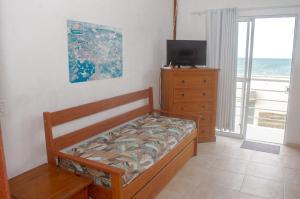 a bedroom with a bed and a dresser and a television at Mirante dos Ingleses in Florianópolis