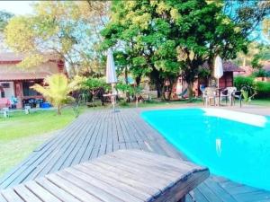 a pool with a wooden deck next to a house at Chalés do Atlântico Sc in Itapoa