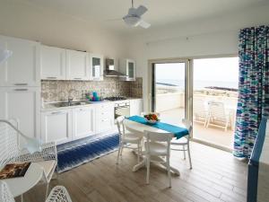 - une cuisine avec une table et des chaises et une vue sur l'océan dans l'établissement Facciamari, à Donnalucata