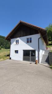 a white building with a garage and a staircase at Maison de vacances La Cernie in Soubey