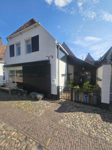 a white house with a gate and a brick driveway at Appartement "de grote Vesting" Elburg in Elburg