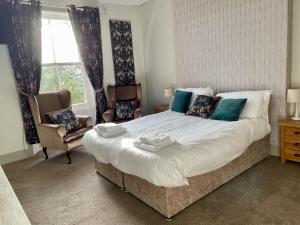 a bedroom with a large bed and two chairs at Turks Head Rothbury in Rothbury