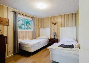 2 Betten in einem Zimmer mit Holzwänden und Holzböden in der Unterkunft Georgian Bay Rockwood 3-bdrm Waterfront Cottage #2 in Dillon