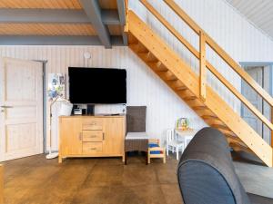 a living room with a tv and a wooden dresser with a staircase at Komfortables Ferienhaus in Mirow in Granzow