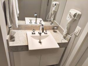 a bathroom with a sink and a hair dryer at Estanconfor Santos - vista mar in Santos