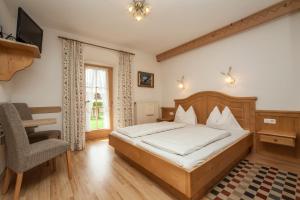 1 dormitorio con 1 cama, 1 silla y TV en Kaiserpension Müllnerhof en Oberndorf in Tirol