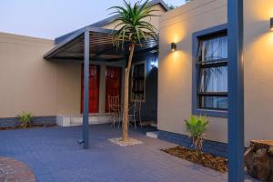 a house with a palm tree in front of it at Hamisi Manor Guest House in Midrand