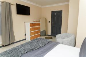 a bedroom with a bed and a dresser and a television at Hamisi Manor Guest House in Midrand