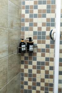 a bathroom with two soap bottles on a tiled wall at Hamisi Manor Guest House in Midrand