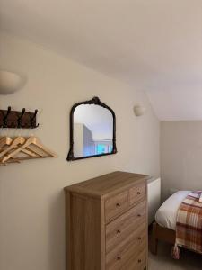 a bedroom with a dresser and a mirror on the wall at New Close Farmhouse in Bransgore