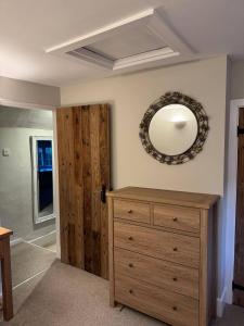 a room with a wooden dresser and a mirror on the wall at New Close Farmhouse in Bransgore +10 photos