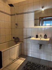 een badkamer met een wastafel, een bad en een spiegel bij City Appartment Neuss in Neuss