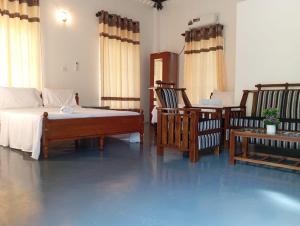 a bedroom with a bed and two chairs and a table at The Shenu Lake House in Dandugama