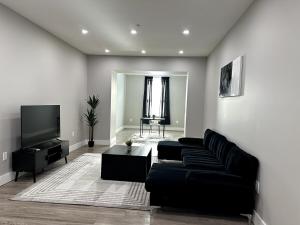 a living room with a black couch and a flat screen tv at Spacious Modern 1 Bedroom RARE Apt w GYM in Albany