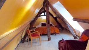an attic room with a bed and a chair at La Longère d'Auberville in Auberville