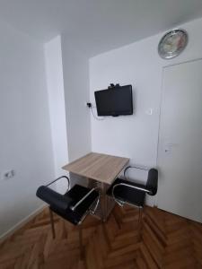 a table and chairs in a room with a tv on the wall at Slatka sobica za dvoje sa upotrebom zajednicke kuhinje i kupaonice in Zagreb