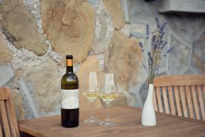 ドルチェアックアにあるTerre Bianche Appartamentiのワイン1本とワイングラス2杯(テーブル上)