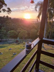 a coffee cup sitting on a window sill with the sunset at Recanto do Divino in Palhoça