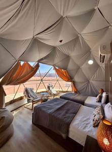 a bedroom with a tent with a bed and chairs at RUM RANIA LUXURU CAMP & Bubbles Hotel in Wadi Rum