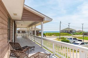 a porch with two chairs and a view of the ocean at Out of the Blue in Kitty Hawk