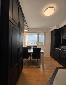 a kitchen with black cabinets and a table with chairs at Le 9 - Basel Airport in Saint-Louis