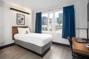 a bedroom with a bed and a desk and a window at Hotel Willo - previously known YWCA Hotel in Vancouver +57 photos
