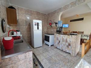 a kitchen with a white refrigerator and a sink at Terra da Luz - Casa de praia CE in Cascavel