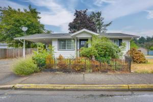 a white house with a fence in front of it at Hot Tub and Fenced Yard Cozy Cottage Grove Home in Cottage Grove