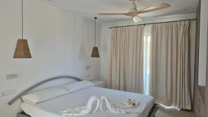 een wit bed in een slaapkamer met een plafondventilator bij Apartamentos Casa Romantica in La Savina +32 foto's