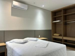Un dormitorio con una cama blanca y aire acondicionado. en Hotel São Francisco, en Itaí