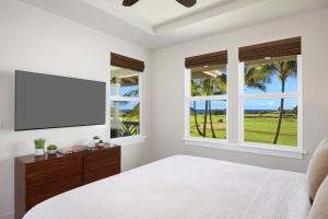 a bedroom with a bed and a flat screen tv at Poipu Retreat with Golf Ocean Views and AC in Koloa