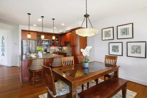 a dining room and kitchen with a wooden table and chairs at Poipu Retreat with Golf Ocean Views and AC in Koloa