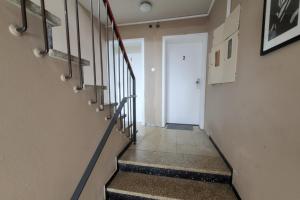 un couloir avec des escaliers et une porte blanche dans l'établissement L21-Apartment Geilenkirchen OT Teveren, 3 Zimmer, 6 Betten, Standardisierte Ausstattung, ideal für Reisende, Pendler, Familien, à Geilenkirchen