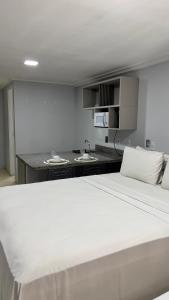 a large white bed in a room with a kitchen at Blue Sunset Family Experience in João Pessoa