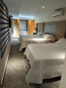 a hotel room with two beds and a television at Finca Hotel la Manuela in Armenia