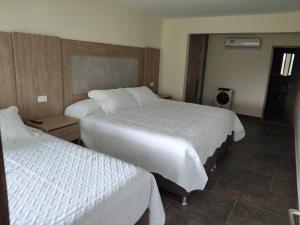 a hotel room with two beds with white sheets at Finca Hotel la Manuela in Armenia