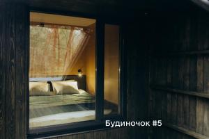 a bedroom with a bed and a mirror in a room at Будиночки для відпочинку ТРОХИ ДАЛІ in Dmitrenki