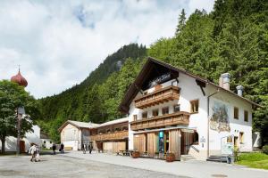 a building in the mountains with people walking around it at Gasthof Salzstadl in Reutte