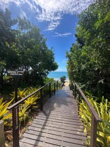 a wooden pathway leading to the beach with the ocean at Casa Da Enseada Azul com 5 SUITES - GUARAPARI in Guarapari