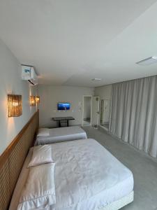 a bedroom with two beds and a table in it at Casa Da Enseada Azul com 5 SUITES - GUARAPARI in Guarapari