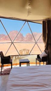 Habitación con cama, 2 sillas y ventana en Fun Camp Wadi Rum, en Wadi Rum