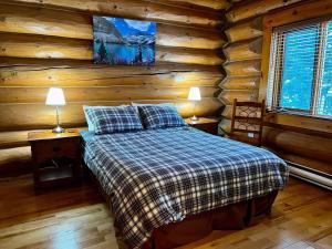 a bedroom with a bed in a log cabin at Chancellor Peak 1BR and Loft Wooden Cabin near Lake Louise in Beaverfoot