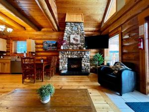 a living room with a stone fireplace in a log house at Chancellor Peak 1BR and Loft Wooden Cabin near Lake Louise in Beaverfoot