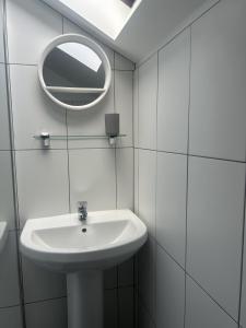 a white bathroom with a sink and a mirror at Richmond, Keswick town centre apartment in Keswick