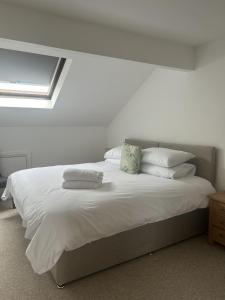 a bedroom with a bed with white sheets and pillows at Richmond, Keswick town centre apartment in Keswick