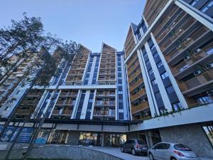 two cars parked in front of a tall building at Apartment Rajski 717 in Zlatibor +30 photos