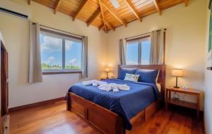 1 Schlafzimmer mit einem Bett mit blauer Bettwäsche und 2 Fenstern in der Unterkunft Infinite Sea - Lower Unit 3 bed 2 bath Caye Caulker in Caye Caulker + 30 Fotos