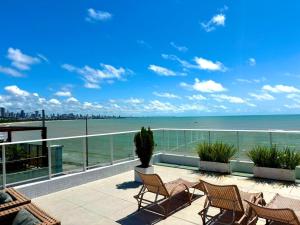 Un balcón con sillas y vista al mar. en Blue Sunset Family Experience - Aptos 101 - 220 - 223 - 224 - 311, en João Pessoa