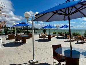 a patio with tables and chairs and blue umbrellas at Blue Sunset Family Experience in João Pessoa